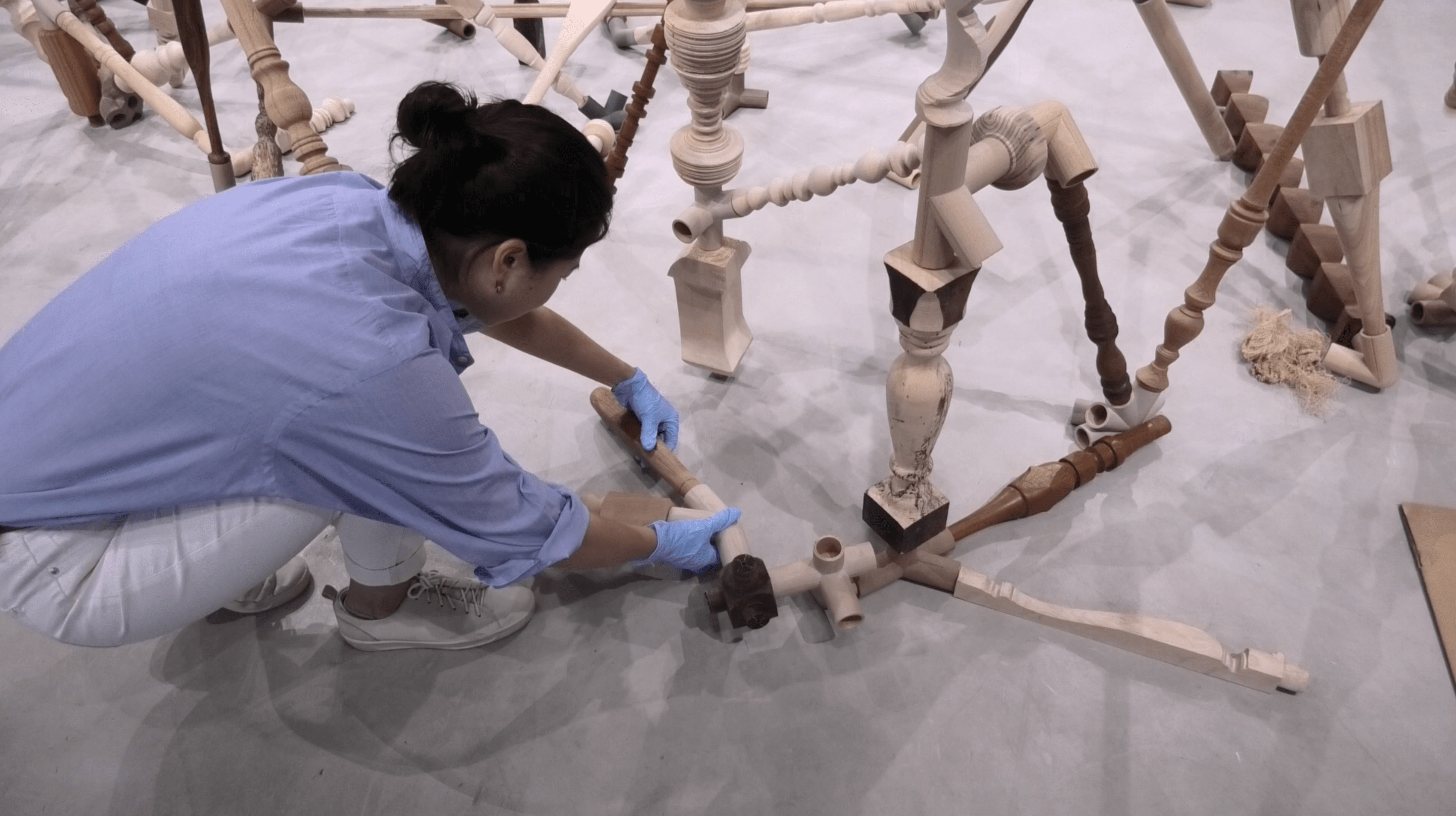 Annie Lye (Gallery Intern) attaching a wooden 'limb' to the artwork Negotiated Differences